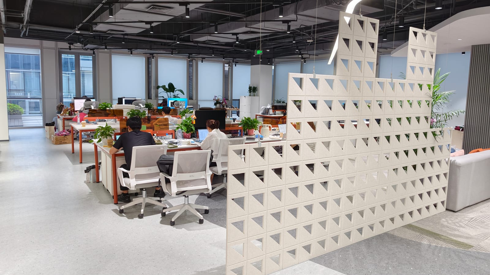 Open-plan workspace in our Hong Kong office, with daylight windows and a perforated divider.